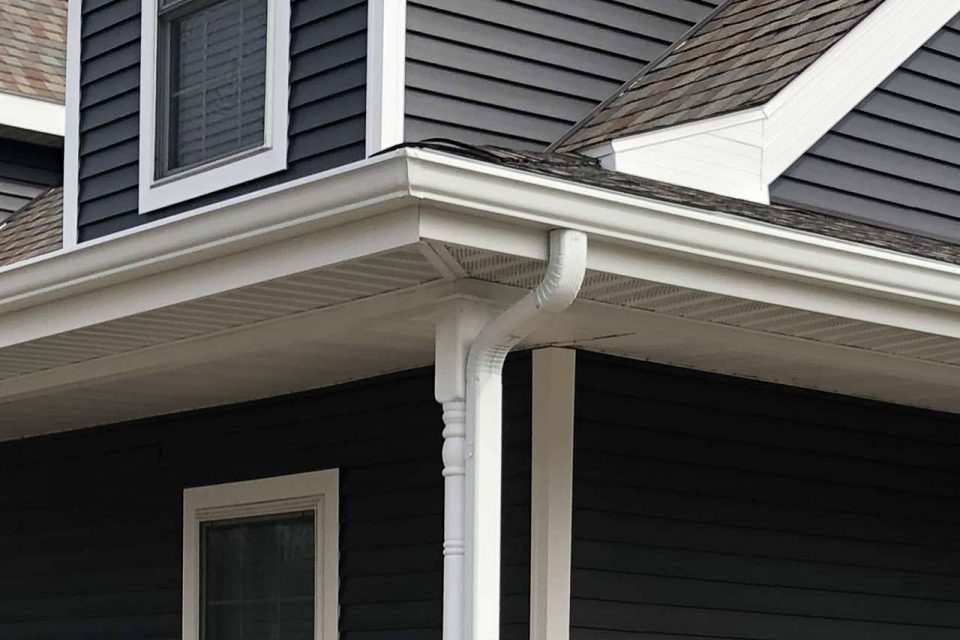 Corner of a dark gray house with white gutters