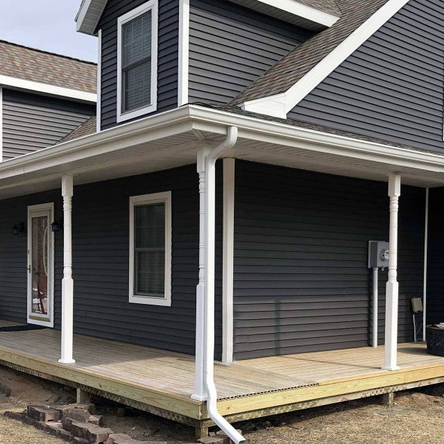 Dark gray new home build with white trim and a white rain gutter system