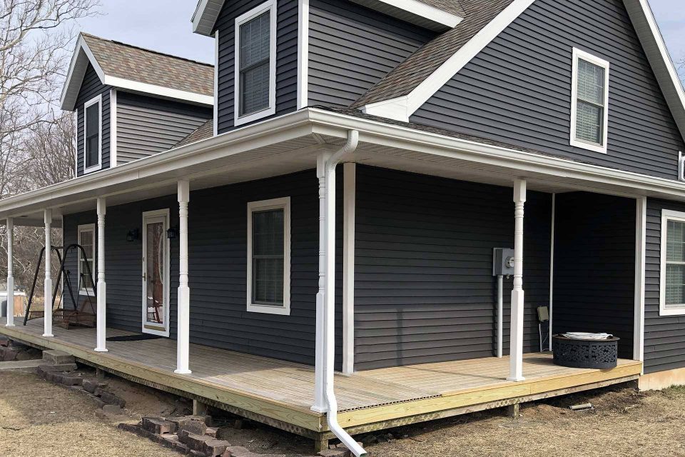 Dark gray new home build with white trim and a white rain gutter system