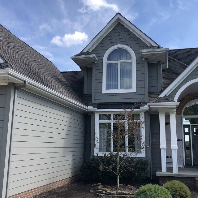 Gray newly built house with white trim and white gutters