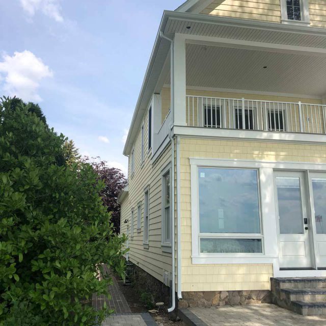 Corner of a pale yellow house with white rain gutters