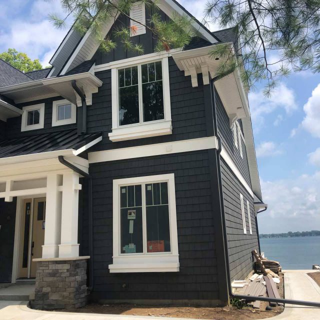 New house built with dark siding and matching customized rain gutters