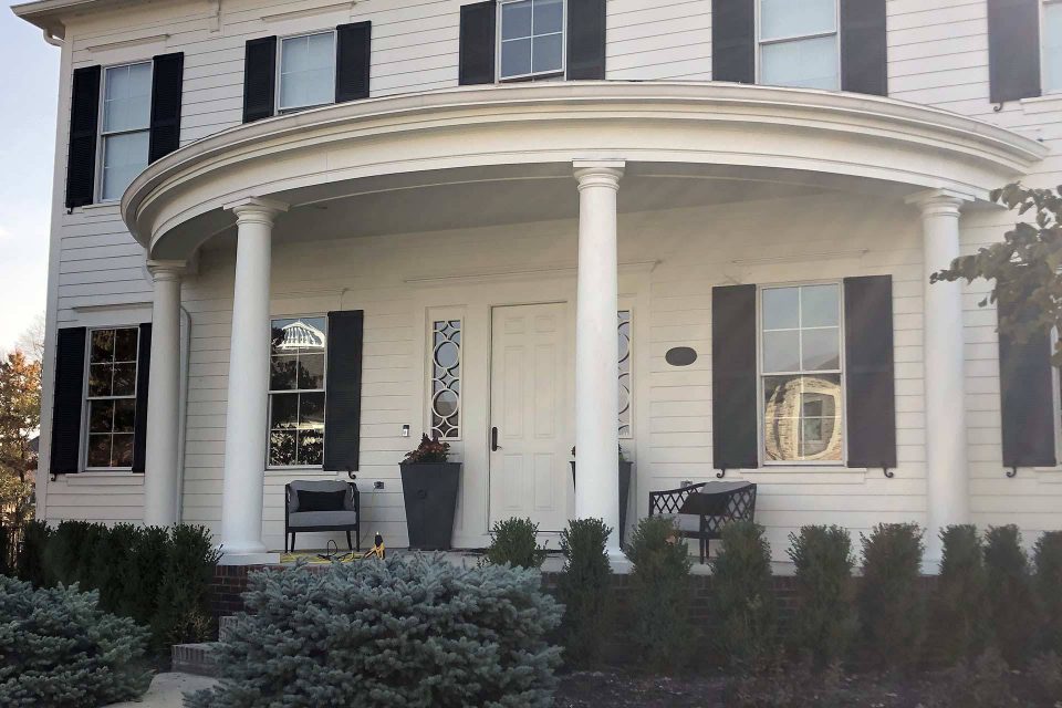 Front of a white house with black shutters and four columns